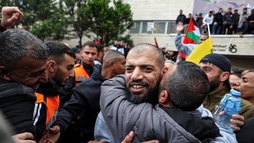 One of the Palestinian prisoners released by Israel embraces a man after disembarking a Red Cross bus in Ramallah