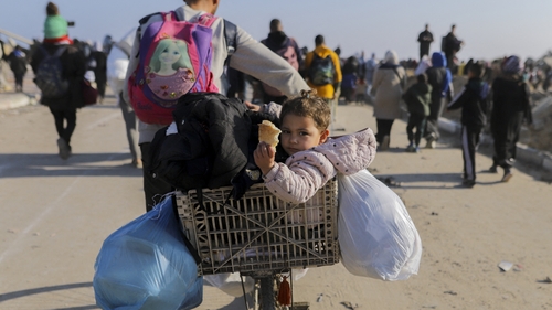 A child sits on the back of a bicycle as thousands of Palestinians return to northern Gaza