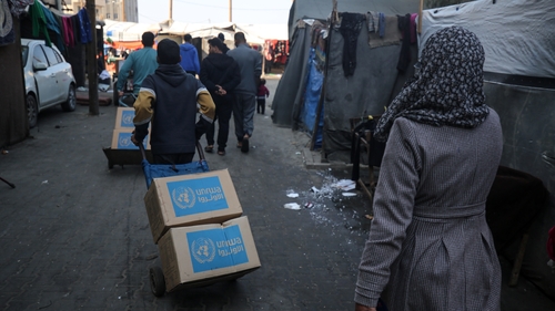 Palestinians transport boxes of food relief supplies delivered by UNRWA in Deir al-Balah