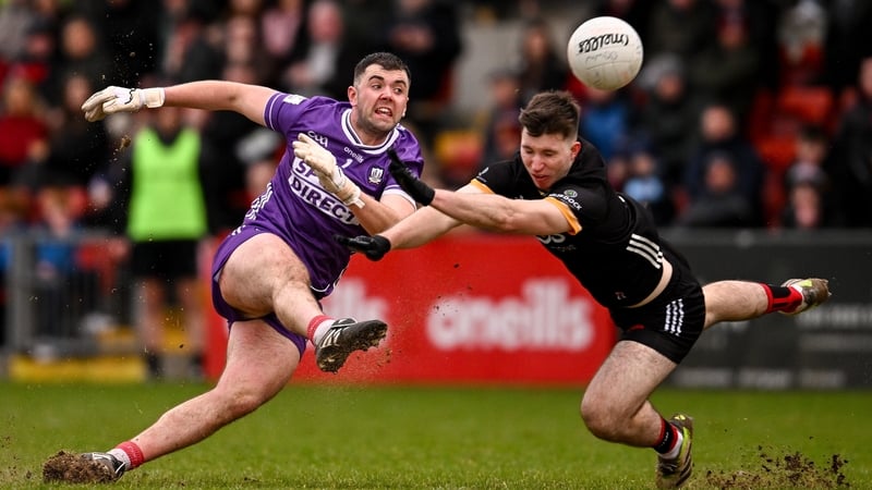 Cork goalkeeper Patrick Doyle kicks a point despite attentions of Down's Peter Fegan