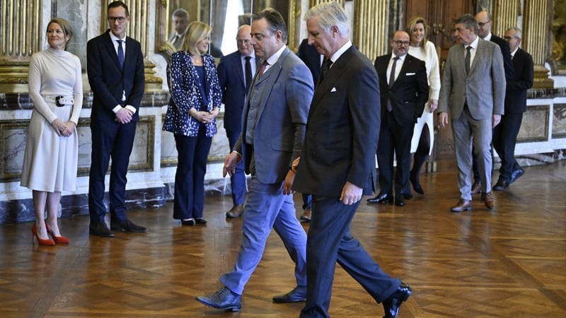 King Philippe (R) walks alongside Bart De Wever during the swearing-in ceremony