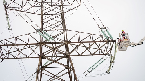 Technicians on a hydraulic platform work to disconnect the major power line between Latvia and Russia in Vilaka