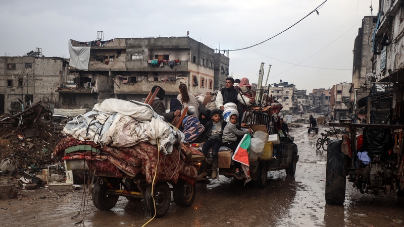 Displaced Palestinians sit in the back of a loaded truck in Jabalia refugee camp