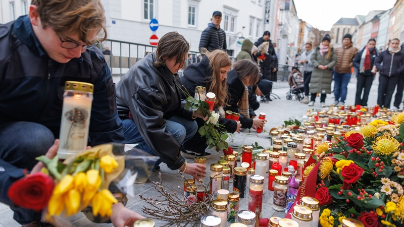 People light candles at the site of the stabbing in Villach, Austria