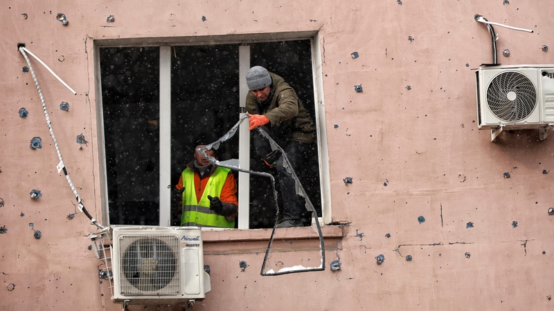 Municipal workers repair a broken window in a residential building destroyed by a Russian drone strike in Odesa
