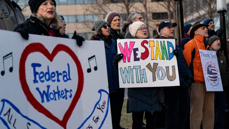 Demonstrators hold signs in support of federal workers outside of the L'Enfant metro station in Washington, DC