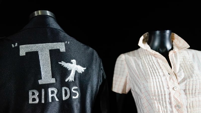 Danny Zuko's (John Travolta) 'Greased Lightnin' T-Birds jacket, left, (est. $100,000 - 200,000) alongside Sandy Olsson's (Olivia Newton-John) screen-matched 'Frosty Palace Jukebox' dress (est. $30,000 - 60,000). Photo credit: Andrew Matthews/PA Wire