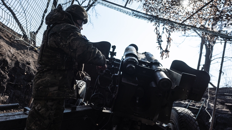 Ukrainian soldiers stand in a trench under camouflage netting amid snowy conditions as they prepare artillery in the direction of Pokrovsk, Ukraine