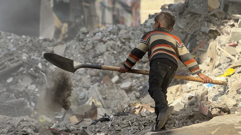 A child clears rubble in Khan Yunis, Gaza from destruction caused by Israeli attacks