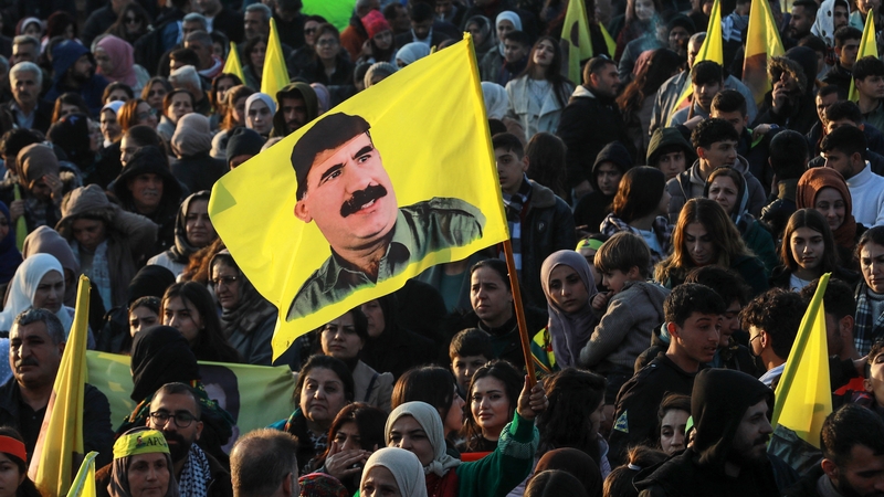 A Syrian Kurdish woman waves a flag bearing a picture of the founder of the PKK Abdullah Ocalan