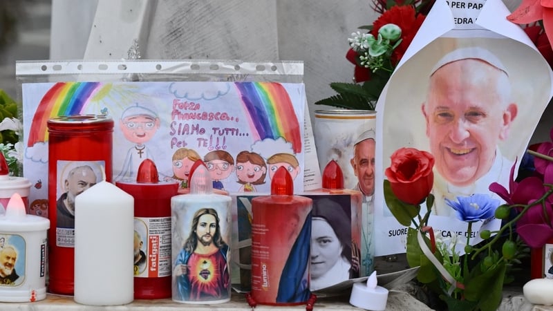 Candles, flowers and a portrait of Pope Francis are laid at the statue of John Paul II outside Gemelli hospital