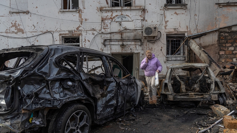 A woman walks past burnt out cars in the courtyard of a building damaged during an overnight drone attack on Odesa