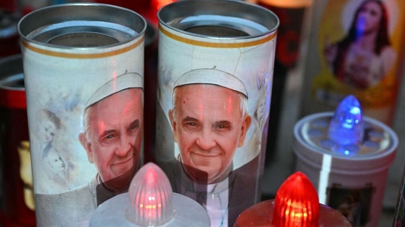 Candles with a image of Pope Francis are laid at the statue of John Paul II outside the Gemelli University Hospital in Rome
