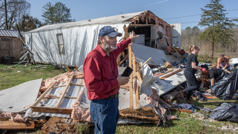 A man stands in front of damaged house after tornado hit in Alabama