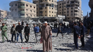 An elderly Palestinian man walks past people gaathered near the rubble of a family house, after it was destroyed in an Israeli strike in al-Sabra neighbourhood in Gaza City