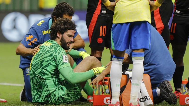 Alisson receives medical attention after colliding with Colombia defender Davinson Sanchez