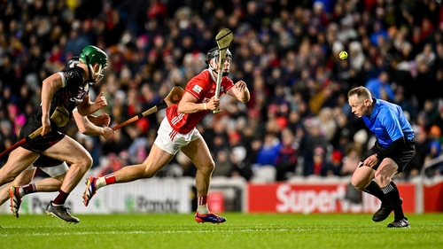 Darragh Fitzgibbon of Cork handpasses the sliotar as referee Chris Mooney ducks out of the way