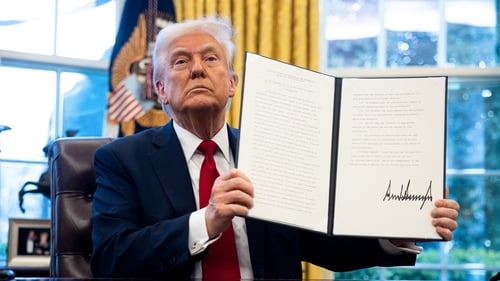 US President Donald Trump displays a signed executive order in the Oval Office of the White House imposing tariffs on cars not made in the US