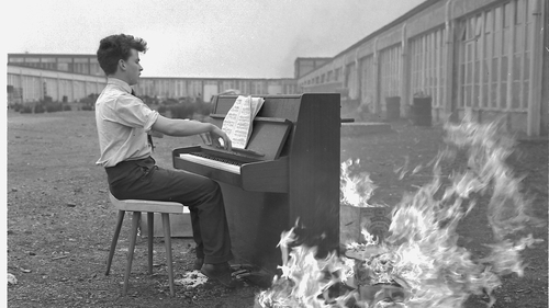 An unidentified man playing a Rippen Lindner piano on fire at Bunratty, Co Clare, March-April 1965 © Special Collections and Archives, Glucksman Library, University of Limerick.