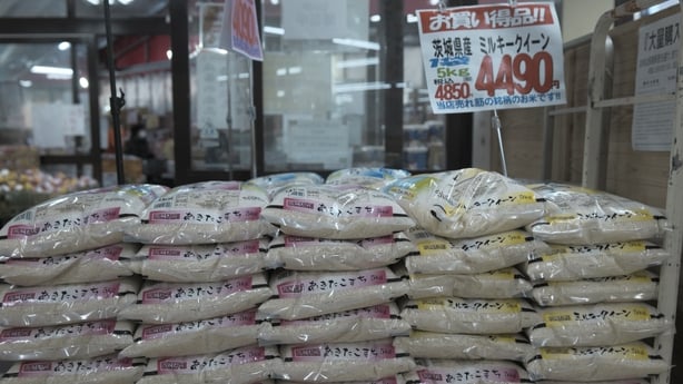 a stack of rice bags in Japan beside a price sign in yen