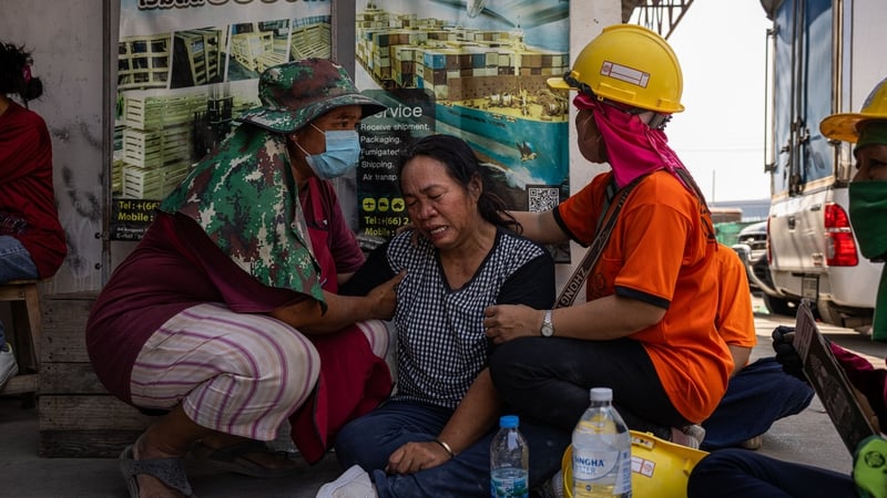 People weep next to a collapsed building near Chatuchak Market in Bangkok