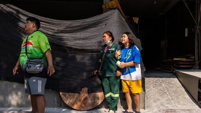 People react next to a collapsed building near Chatuchak Market in Bangkok