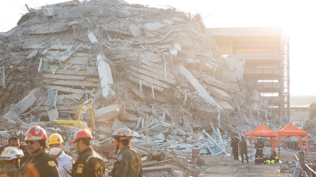 Workers stand next to debris left in the wake of the earthquake in Bangkok