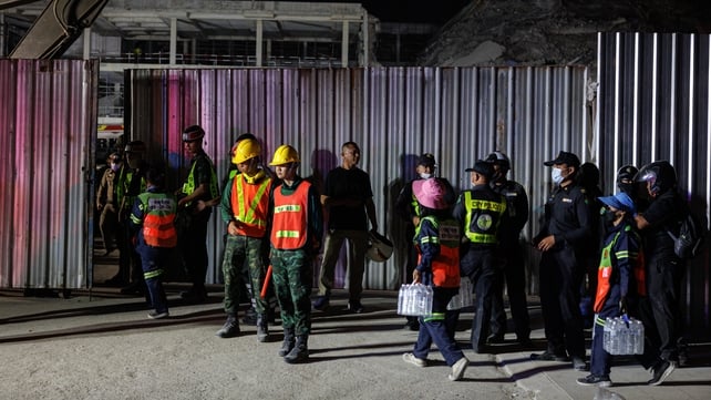 Emergency workers carry cases of water as they work into the night in Bangkok, Thailand