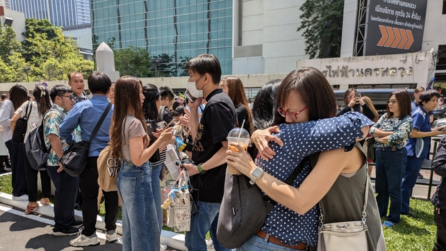 People embrace outside an office building in Bangkok