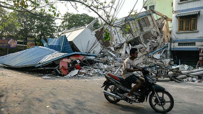 A man rides his motorbike past a collapsed building in Mandalay