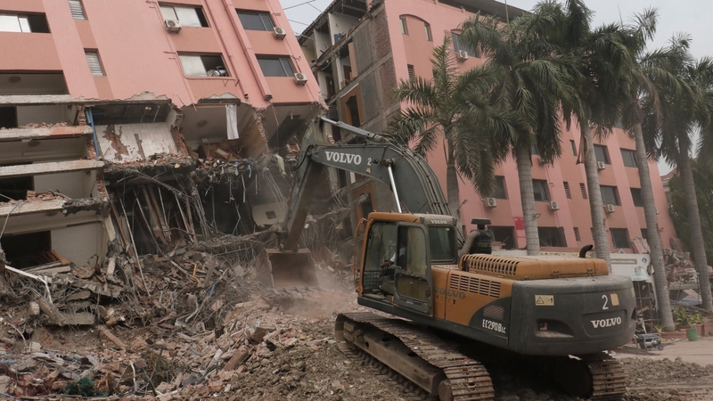 Heavy construction equipment is used to clear rubble at the site of a collapsed building in Mandalay