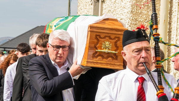 Mick O'Dwyer's son John, as well as grandsons, carry his coffin from the church, led by piper Dermot Walsh