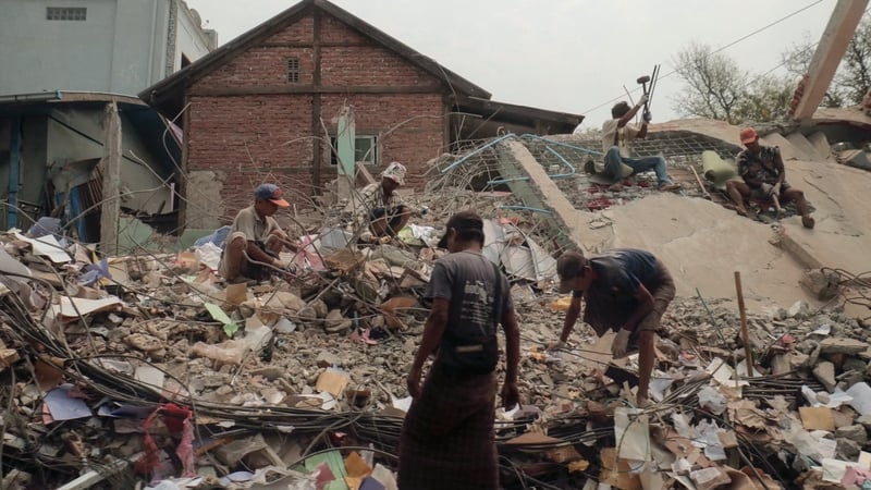 People sort through the rubble of a collapsed building in Mandalay