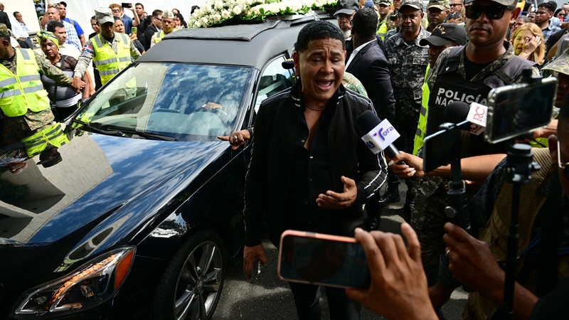 A man reacts as the hearse carrying the coffin of famed merengue singer Rubby Perez, who died in the disaster