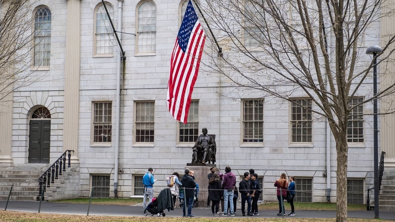 People gather around the John Harvard Statue on the Harvard University campus in Cambridge, Massachussetts