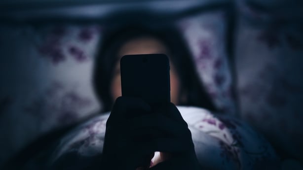 Man texting on his phone in bed at night