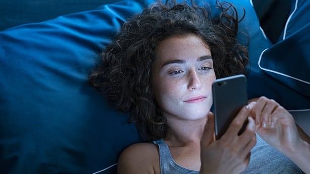 Man using smartphone in bed at night
