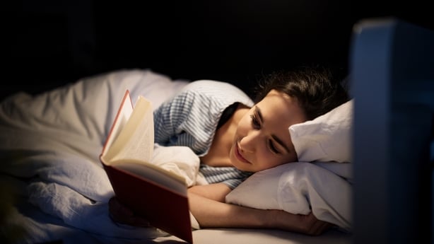 Woman with hands under cheek sleeping in bed