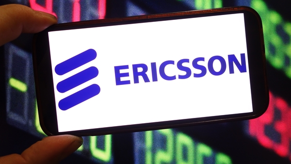 a hand holding a mobile phone with the Ericsson logo on it