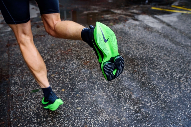 Nike running shoes ALPHAFLY NEXT%. Controversial green athletics shoe on legs of professional athlete running on the road.