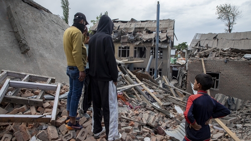 Kashmiri people inspect the remains of a demolished house following exchanges of fire
