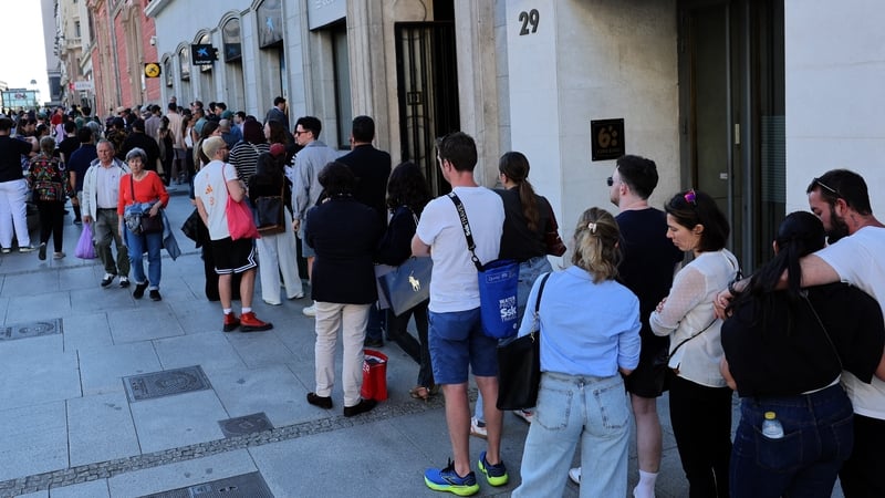 People queue to use an ATM in Madrid