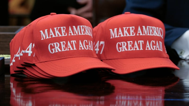 A stack of 'Make America Great Again' hats are seen on the Resolute Desk in the Oval Office at the White House