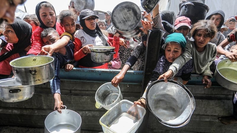Displaced Palestinians, including children, crowd to receive hot meals distributed by charities in the Al-Mawasi area of Khan Yunis, southern Gaza