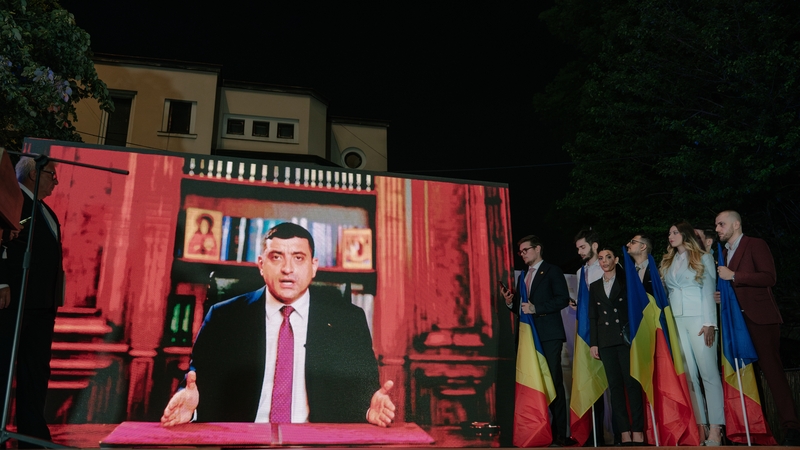 George Simion shown on screen addressing supporters after polls closed in the first round of voting in the election