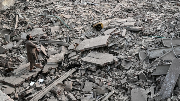 Locals stand on the debris of destroyed structures at a government department in Pakistan after India's attacks