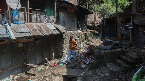 A Kashmiri man walks near damaged shops after shelling from Pakistan in Uri