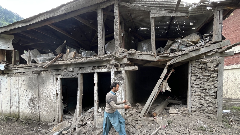 Residents remove debris and clean up damage caused by an attack in Pakistan-administered Kashmir