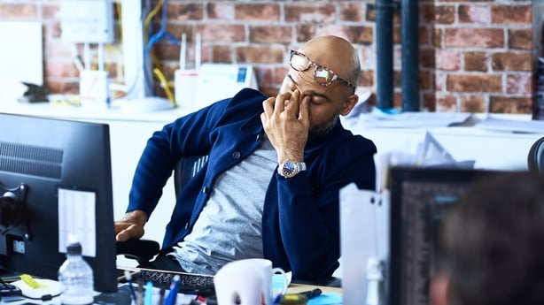 a person sitting at a desk with his hand on his face in frustration