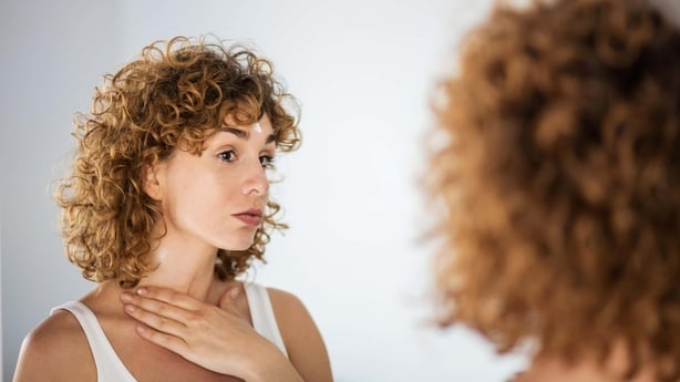 young curly woman using skin cream on in a mirror